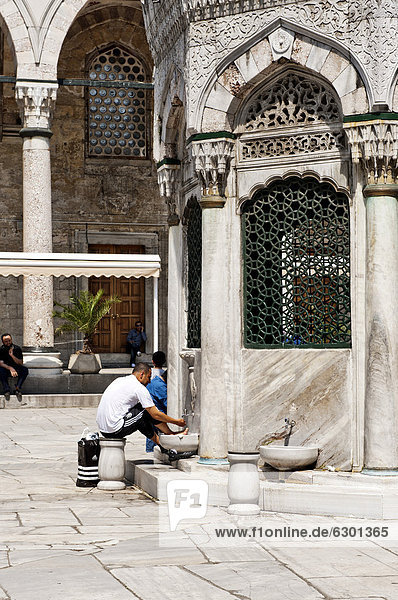 Man washing his feet in the washhouse in the courtyard of the New Mosque  Yeni Cami  Istanbul  Turkey