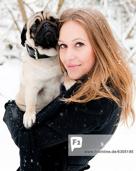 Junge Frau mit einem Mops im Schnee  Portrait