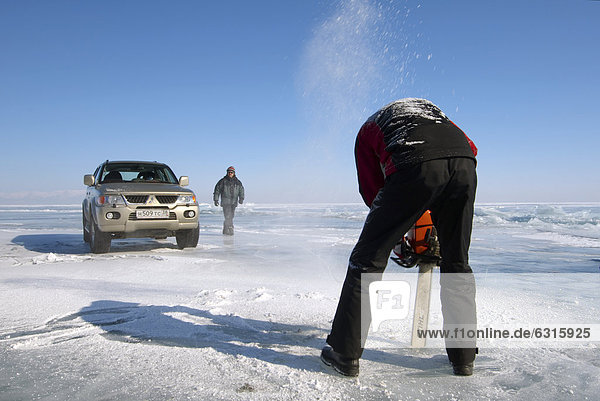 Mann beim Sägen eines Eislochs zum Eistauschen  im Baikalsee  Insel Olchon  Sibirien  Russland  Eurasien  Asien