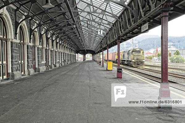 Bahnsteig mit einfahrendem Zug historisches Bahnhofsgebäude Dunedin Südinsel Neuseeland Ozeanien