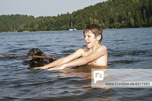 Junge spielt im See mit seinem Jagdhund