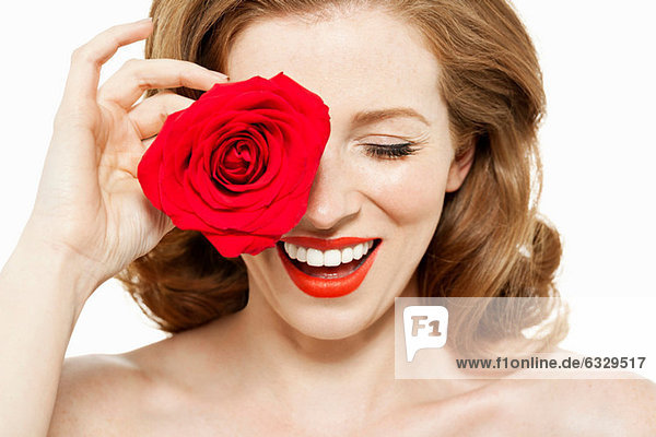 Woman covering eye with red rose