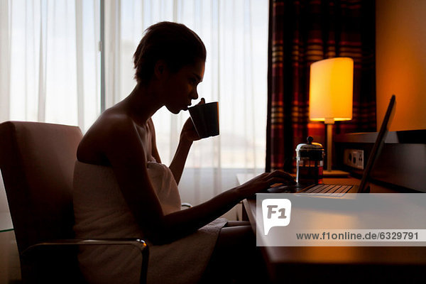 Junge Frau sitzt am Laptop im Hotelzimmer