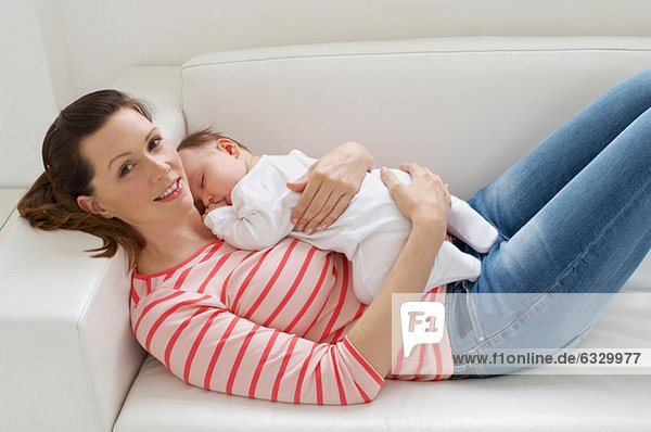 Woman and baby girl resting on sofa
