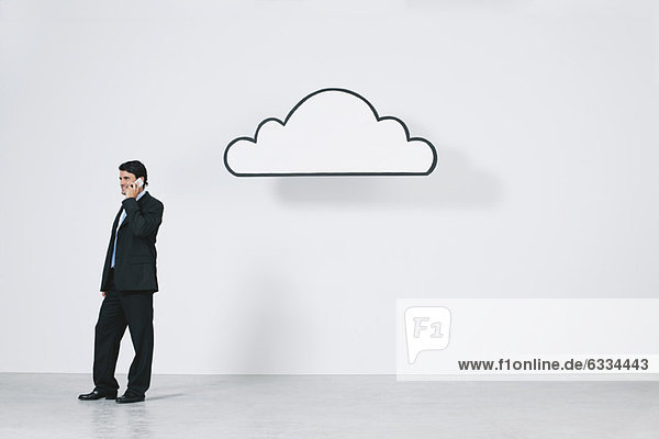 Geschäftsmann im Gespräch auf dem Handy in der Nähe der grafischen Wolke für Cloud Computing