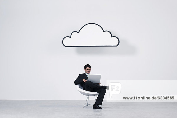 Geschäftsmann  der einen Laptop unter der Wolke benutzt  der Cloud Computing repräsentiert.