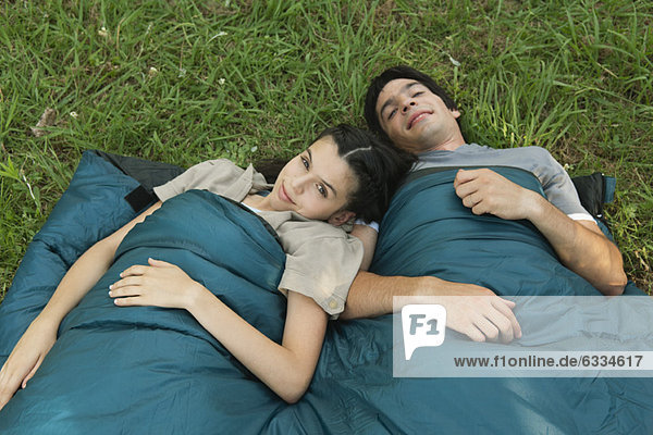 Junges Paar teilt sich den Schlafsack im Feld