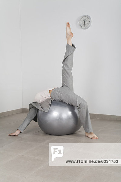 Geschäftsfrau beim Stretching auf dem Fitnessball im Büro