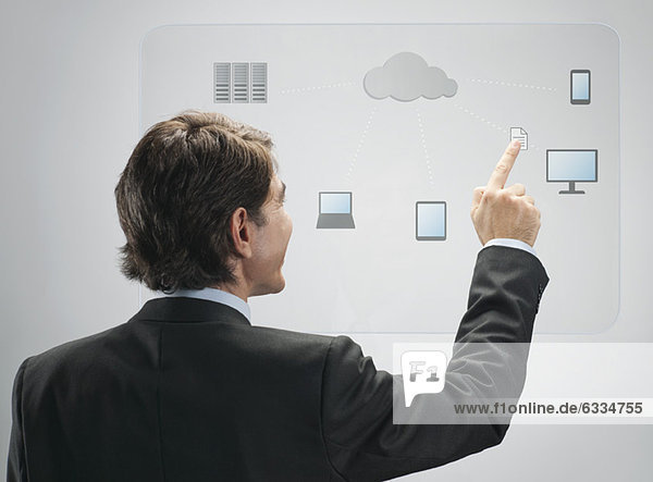 Geschäftsmann  der die Cloud Computing-Technologie auf einer fortschrittlichen Touchscreen-Oberfläche nutzt.