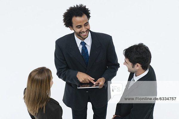Geschäftspartner chatten  während der Kollege ein digitales Tablett benutzt