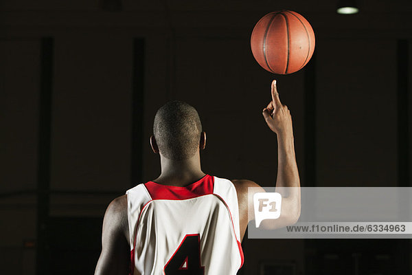 Basketball player spinning basketball atop finger  rear view