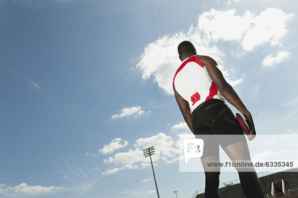 Male athlete holding discus  rear view