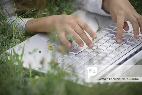 Mädchen mit Laptop-Computer im Gras  beschnitten