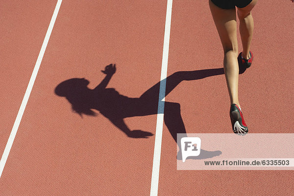 Sportlerin  die auf der Bahn läuft  niedriger Abschnitt  Fokus auf Schatten