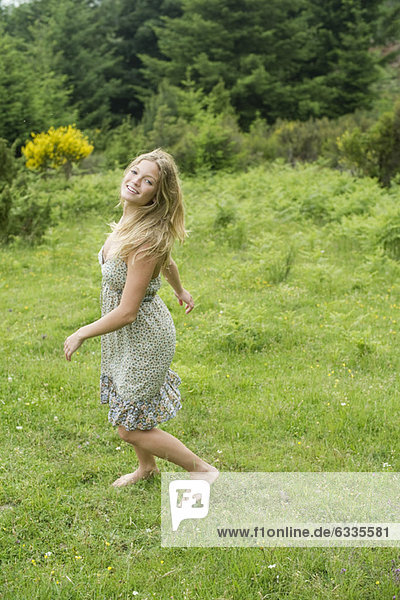 Young woman walking on meadow with barefeet