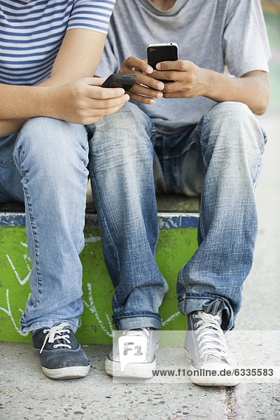 Young men using cell phones  low section