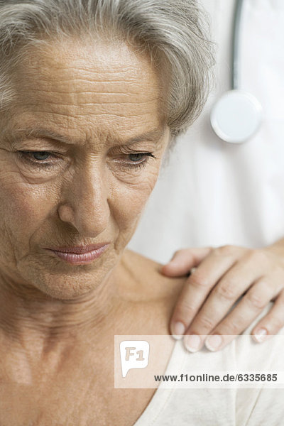 Ältere Frau  die schlechte Nachrichten von einem fürsorglichen Arzt erhält.