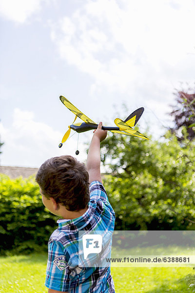 Junge spielt mit Spielzeugflugzeug im Freien