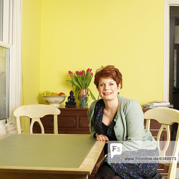Lächelnde Frau am Küchentisch sitzend