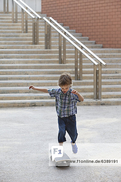 Junge spielt mit Skateboard im Freien