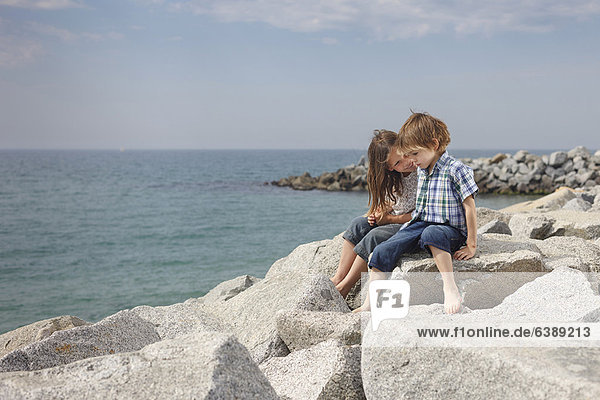 Children talking on rocks at beach