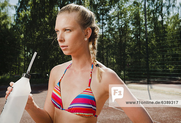 Woman drinking water on tennis court