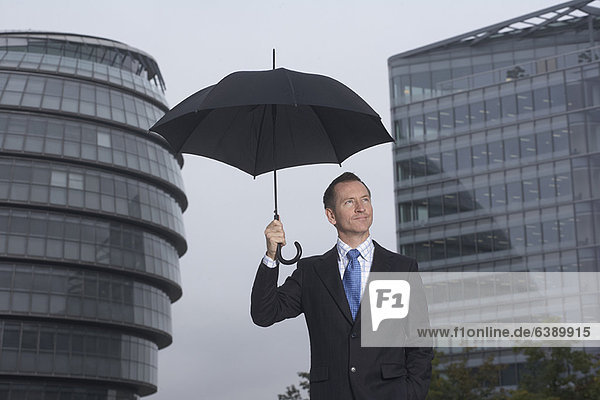 Geschäftsmann steht unter dem Schirm