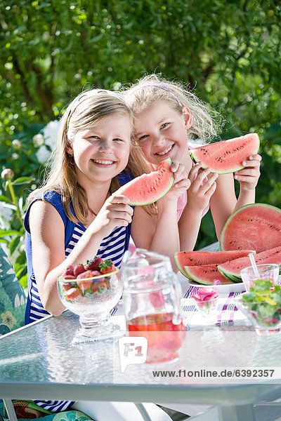 Two sisters eating watermelon in the garden
