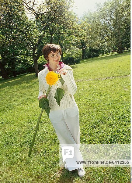 Frau mit Sonnenblume auf einer Wiese