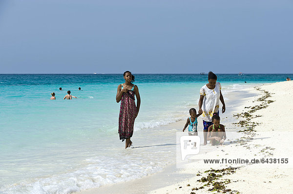 Woman and children strolling along the beach in Kendwa Rocks  north coast of Zanzibar  Tanzania  Africa