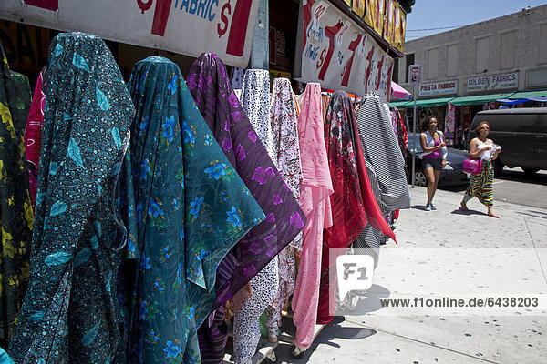 Kleidung und Stoffe zum Verkauf auf dem Bürgersteig vor Läden im Mode-Viertel von Los Angeles Kalifornien USA