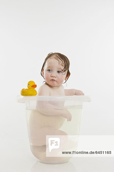 Ein kleines Mädchen in einem Eimer mit Wasser.