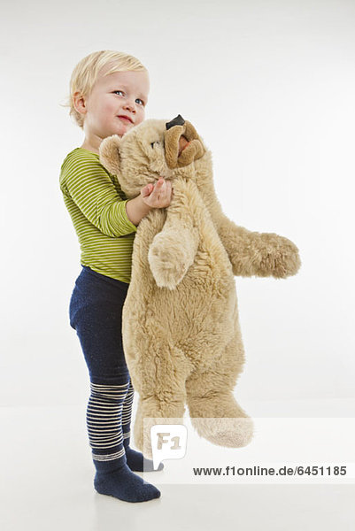 Ein Kleinkind hält einen Teddybären.