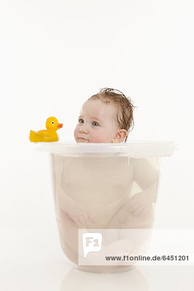 Ein kleines Mädchen  das in einem Eimer mit Wasser sitzt.
