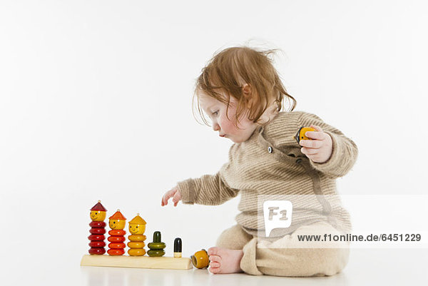 Ein kleines Mädchen spielt mit einem hölzernen Stapelspielzeug
