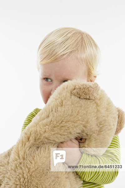 Ein Kleinkind  das einen Teddybären umarmt.