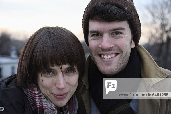 A young couple side by side  outdoors in cold weather