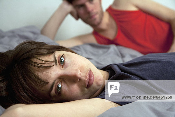 Ein junges unglückliches Paar  das im Bett liegt.