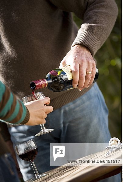 Ein Mann schenkt einer Frau ein Glas Wein ein.