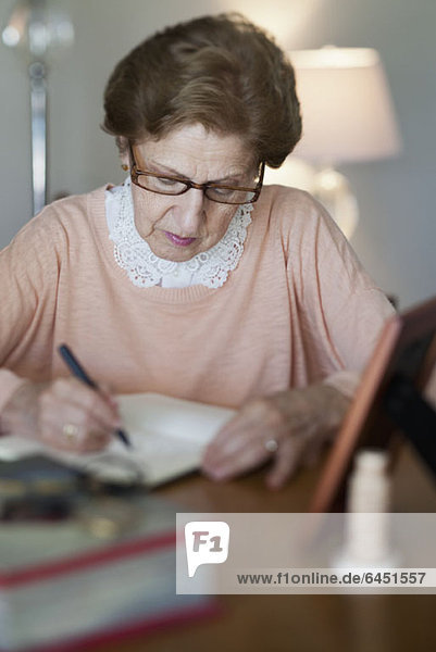Eine ältere Frau  die in ein Notizbuch schreibt.