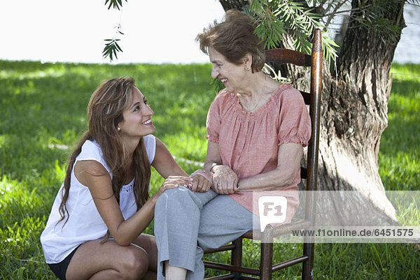 Porträt einer älteren Frau und einer jungen Frau  die zusammen im Freien sitzen.