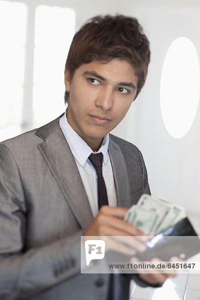 Ein Geschäftsmann  der Geld aus seiner Brieftasche nimmt.