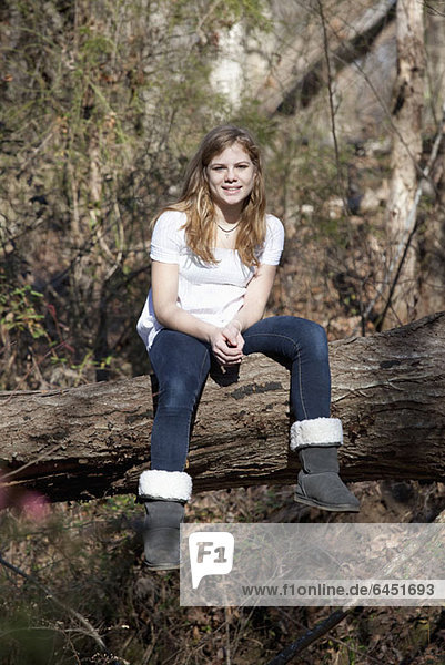 Girl sitting on tree trunk in Mooresville  North Carolina  USA