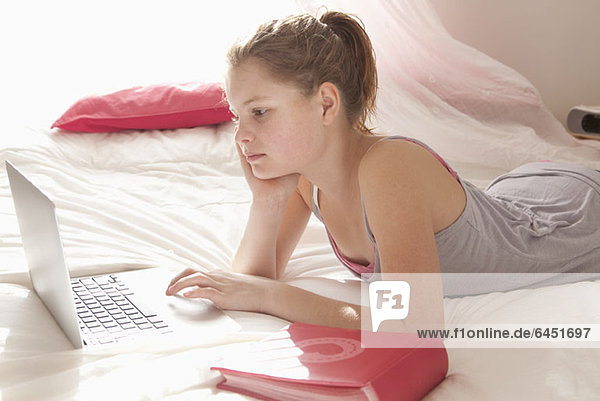 Mädchen im Bett bei den Hausaufgaben