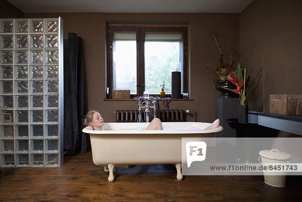A woman taking a bubble bath in a claw foot tub