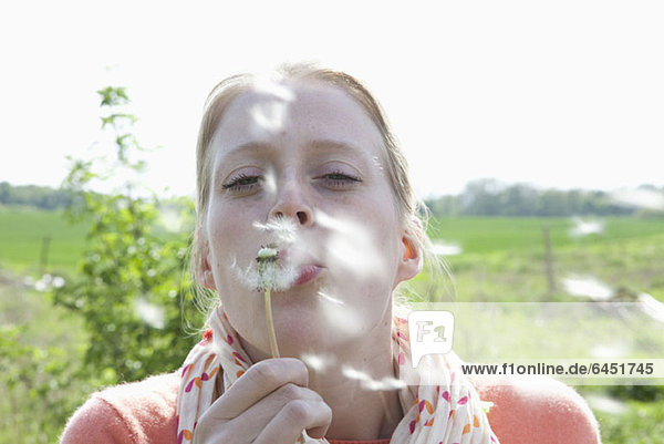 A woman blowing on a dandelion  close-up
