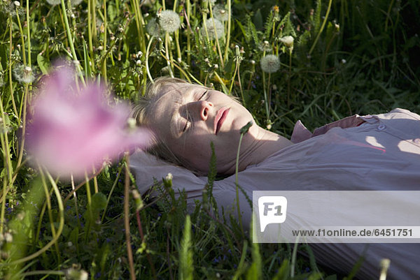 Eine Frau im Gras liegend  schlafend  Nahaufnahme