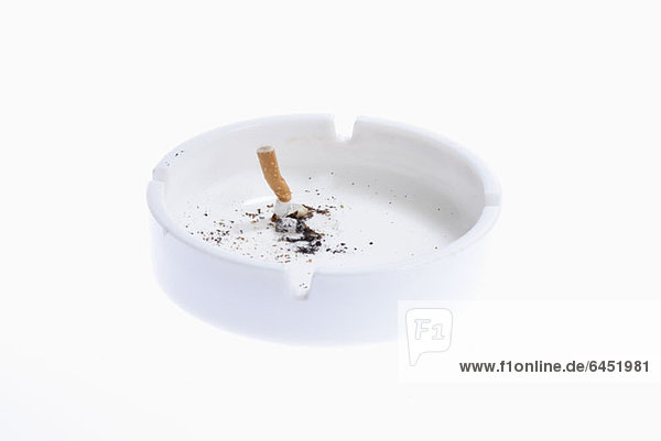 Ein Zigarettenstummel in einem weißen Aschenbecher.