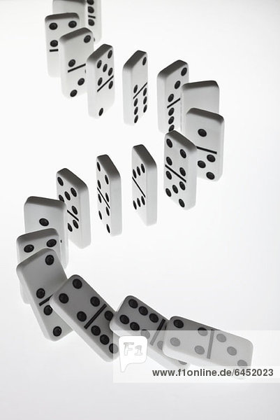 Dominosteine in einer Reihe  die in einer Kettenreaktion umfallen.