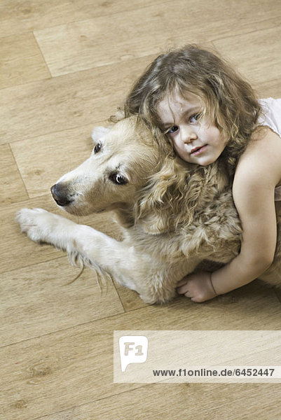 Ein junges Mädchen  das einen Hund umarmt.